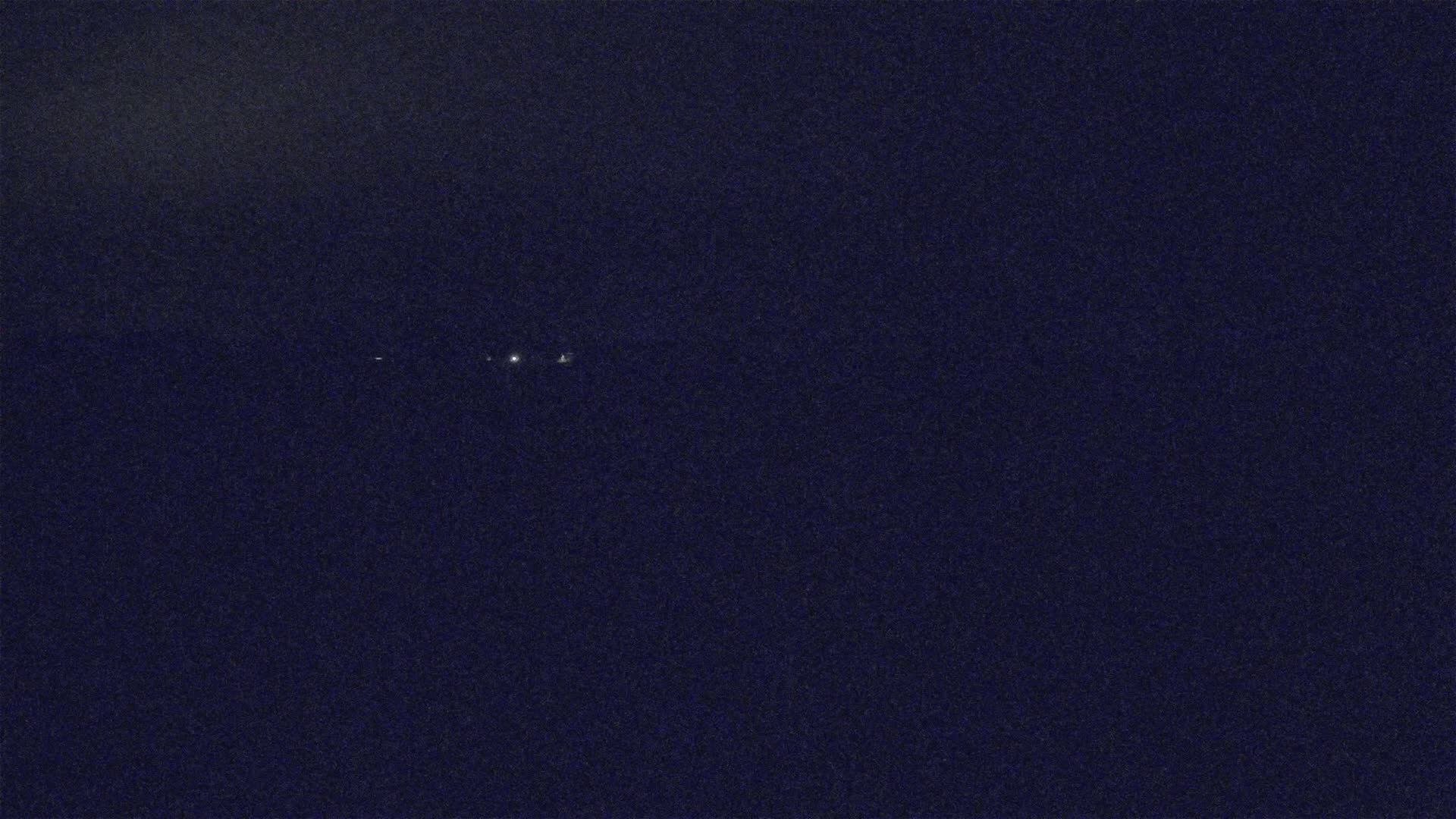 A dark, nighttime sky shows a few faint lights in the distance.