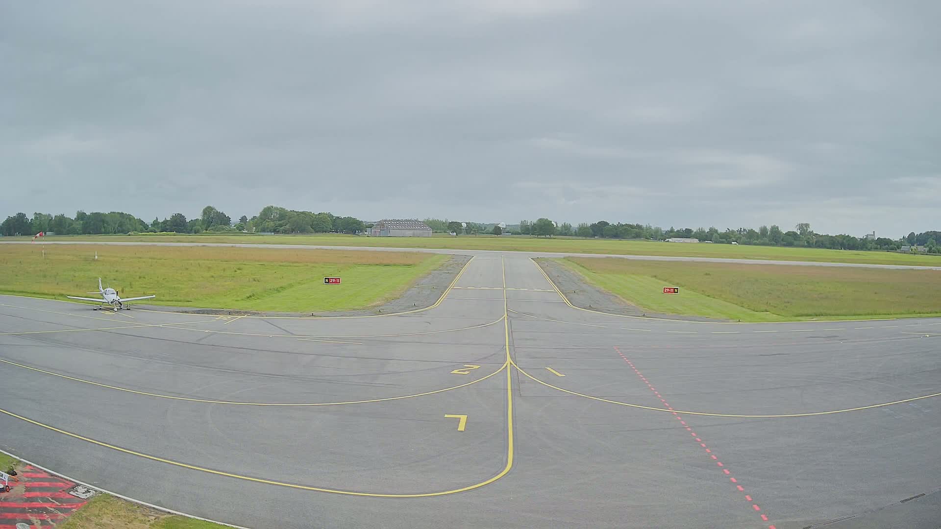 A small airplane sits on a tarmac at an airfield under an overcast sky.