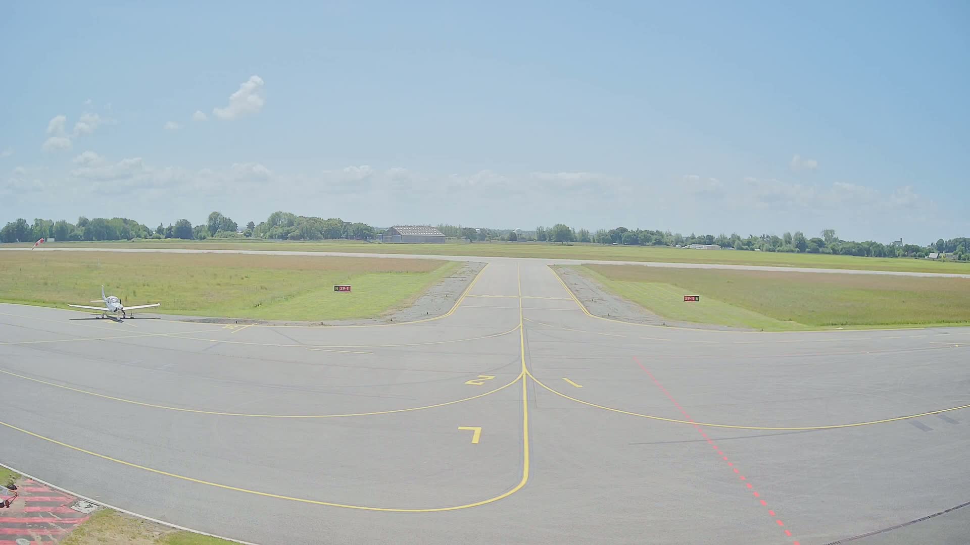 A small airplane sits on a tarmac at an airport on a partly sunny day.