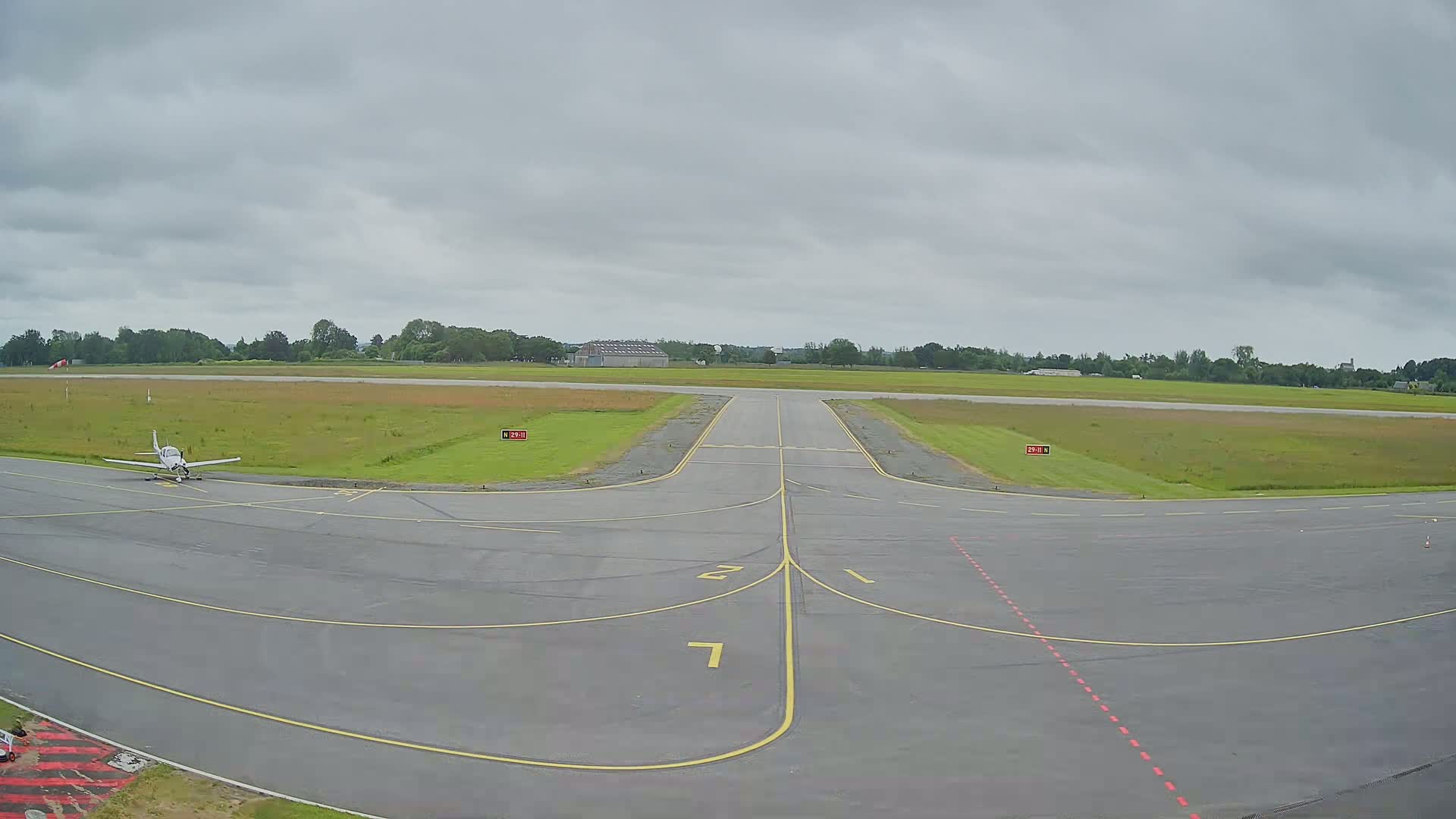 A small airplane sits on a tarmac at an airfield under an overcast sky.