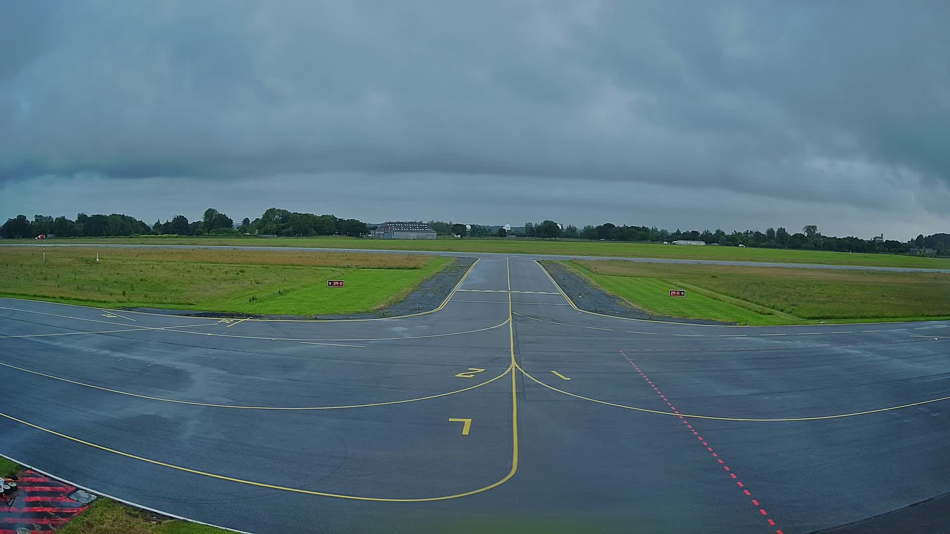 A tarmac runway at an airport under an overcast sky.