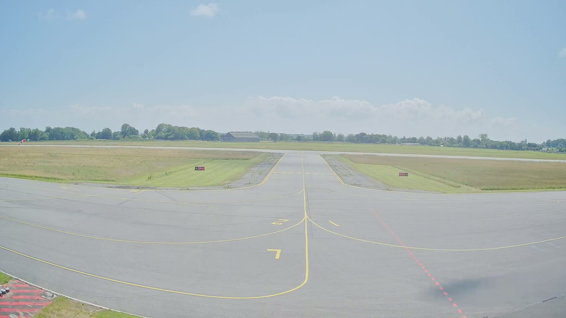 A runway at a small airport on a partly cloudy day.
