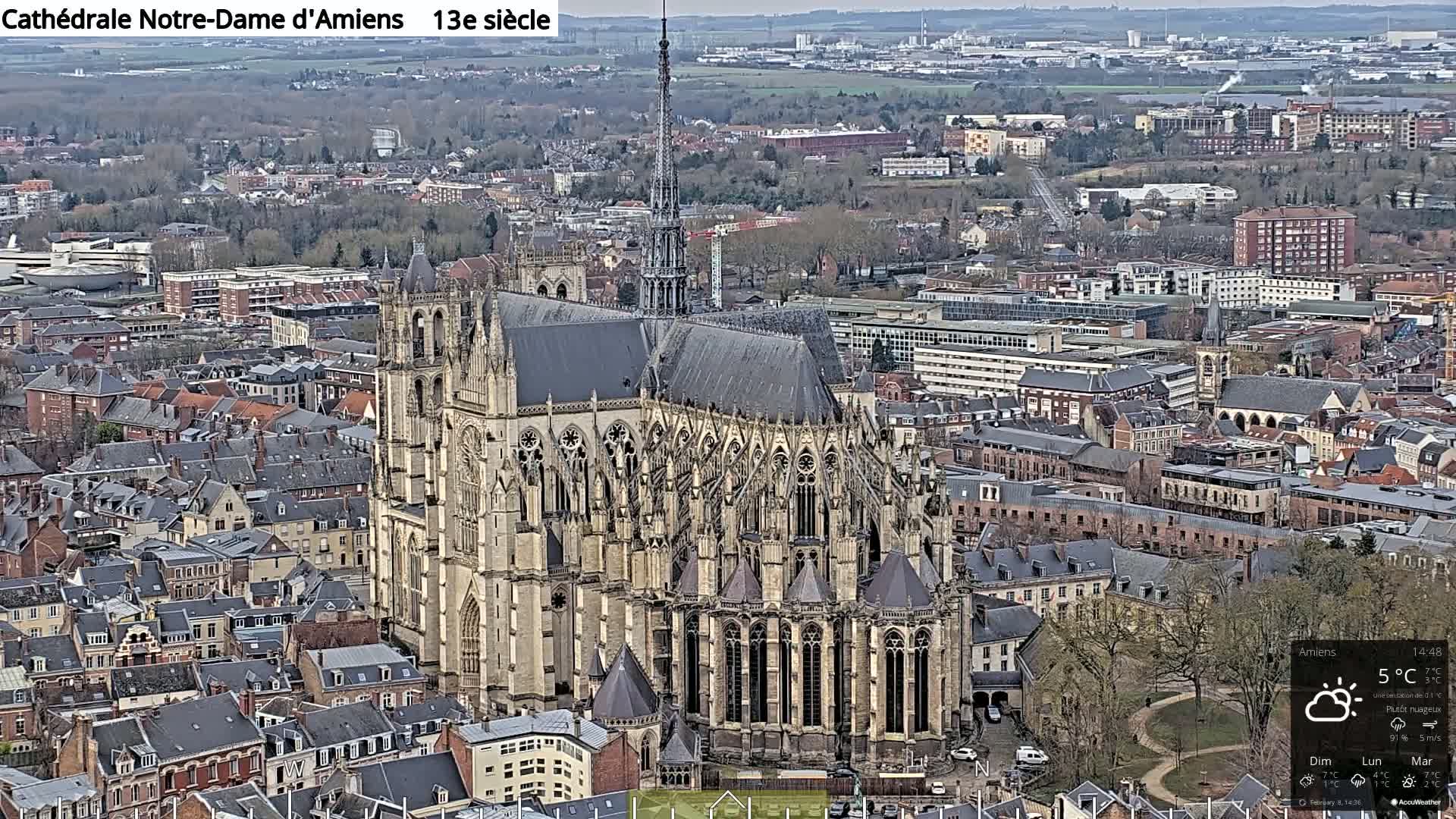 A large cathedral sits in the center of a city on an overcast day with a temperature of 5°C.