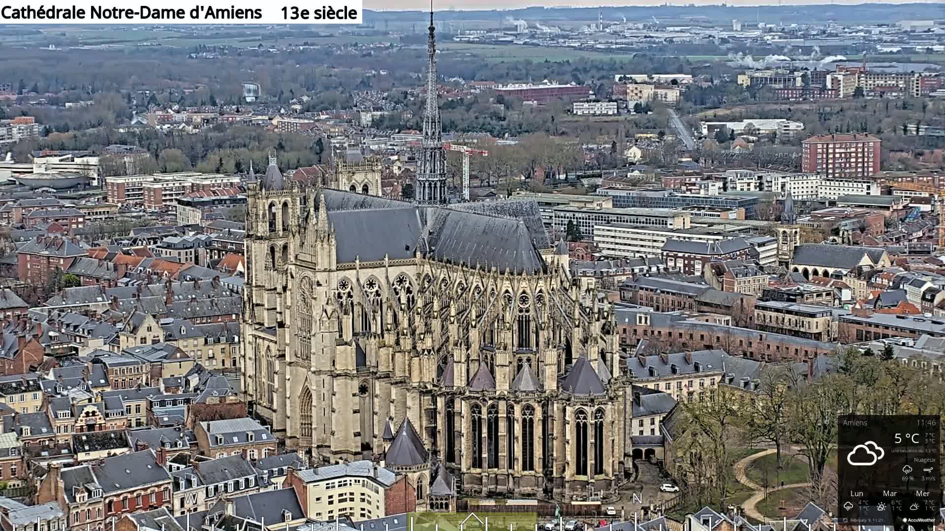 A large cathedral sits in the center of a city on an overcast day.