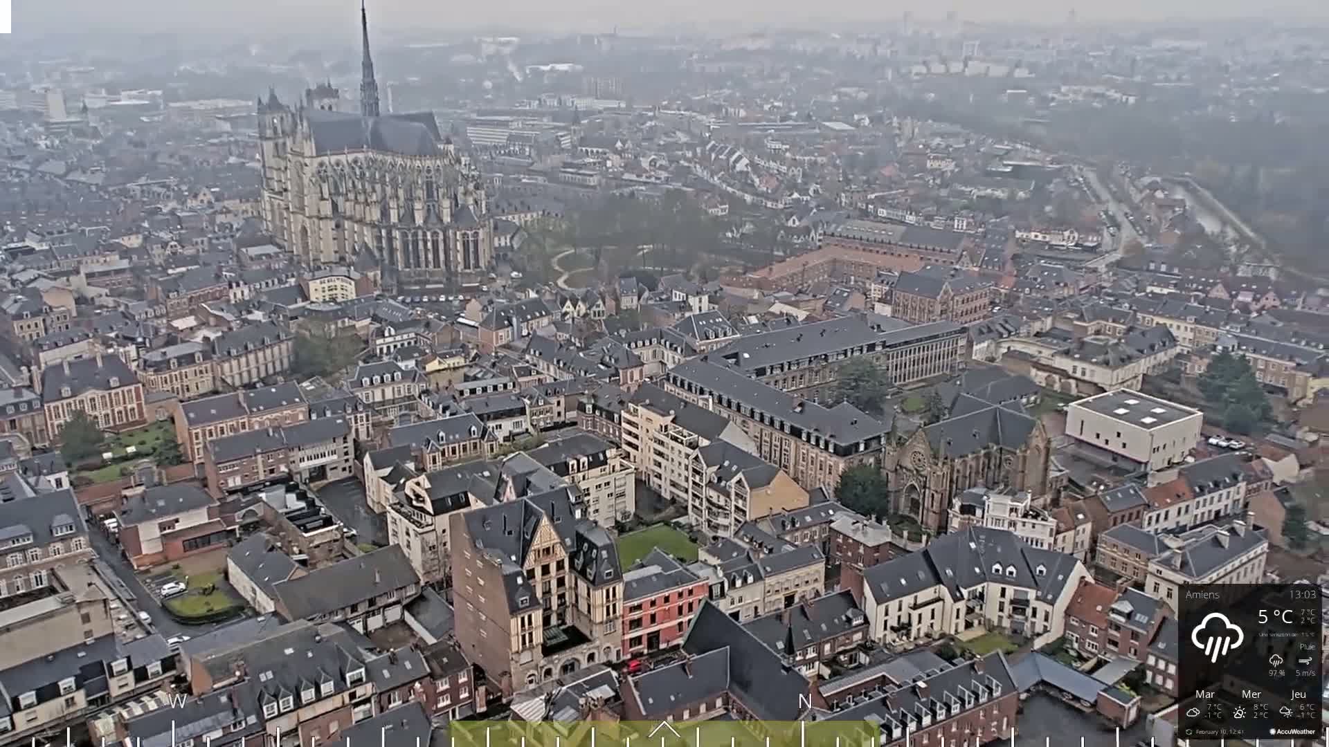 A high-angle, long shot of a city on an overcast day, showing a large cathedral and many buildings of varying sizes and architectural styles.