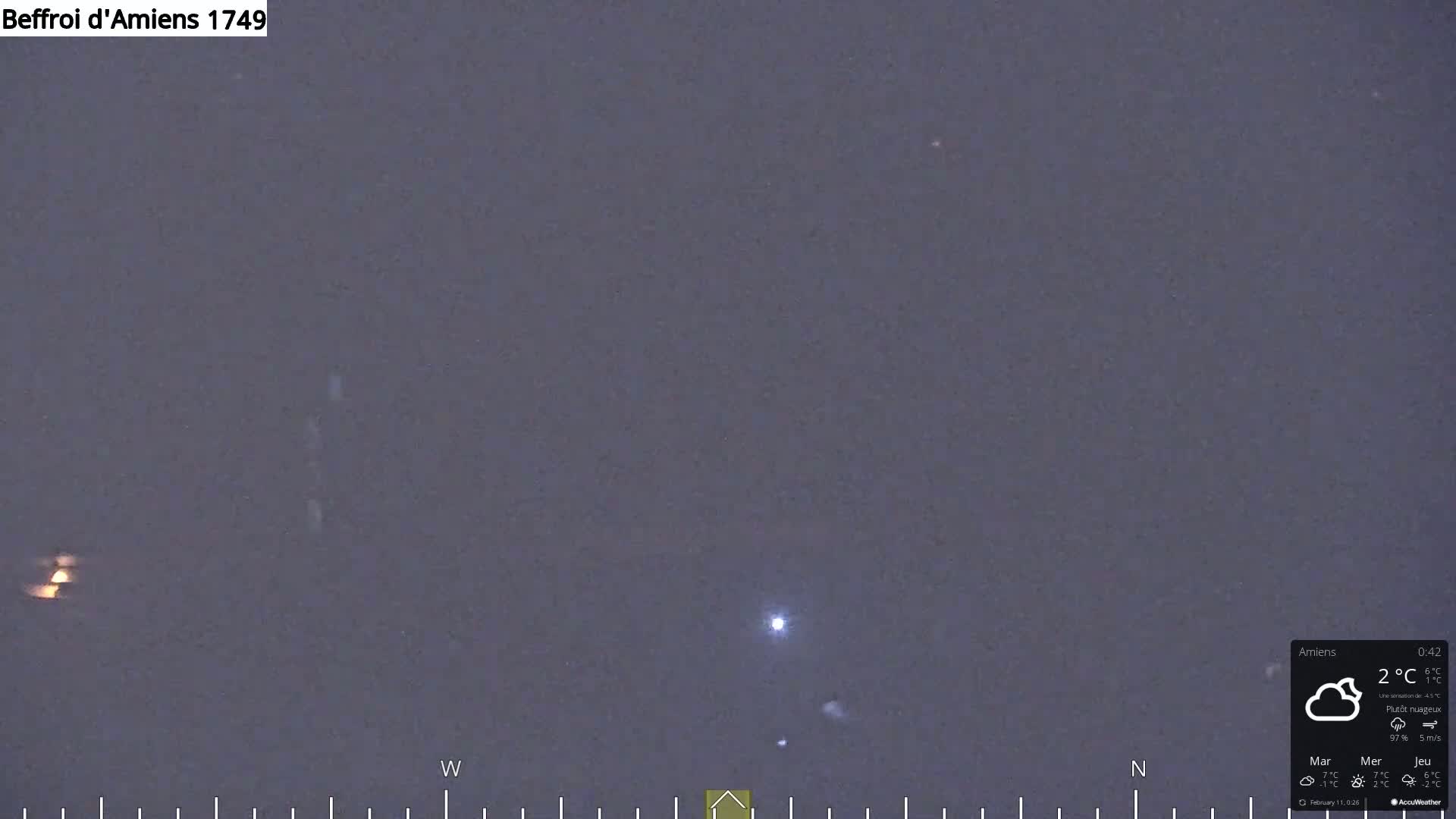 A nighttime long shot of a mostly cloudy sky shows a few distant lights.