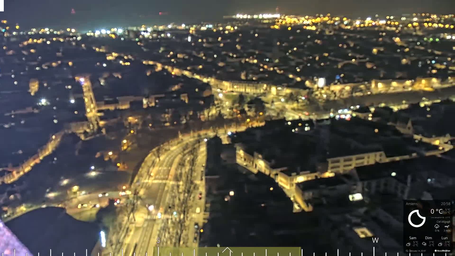 A nighttime aerial view of a city with illuminated streets and buildings under a clear sky.