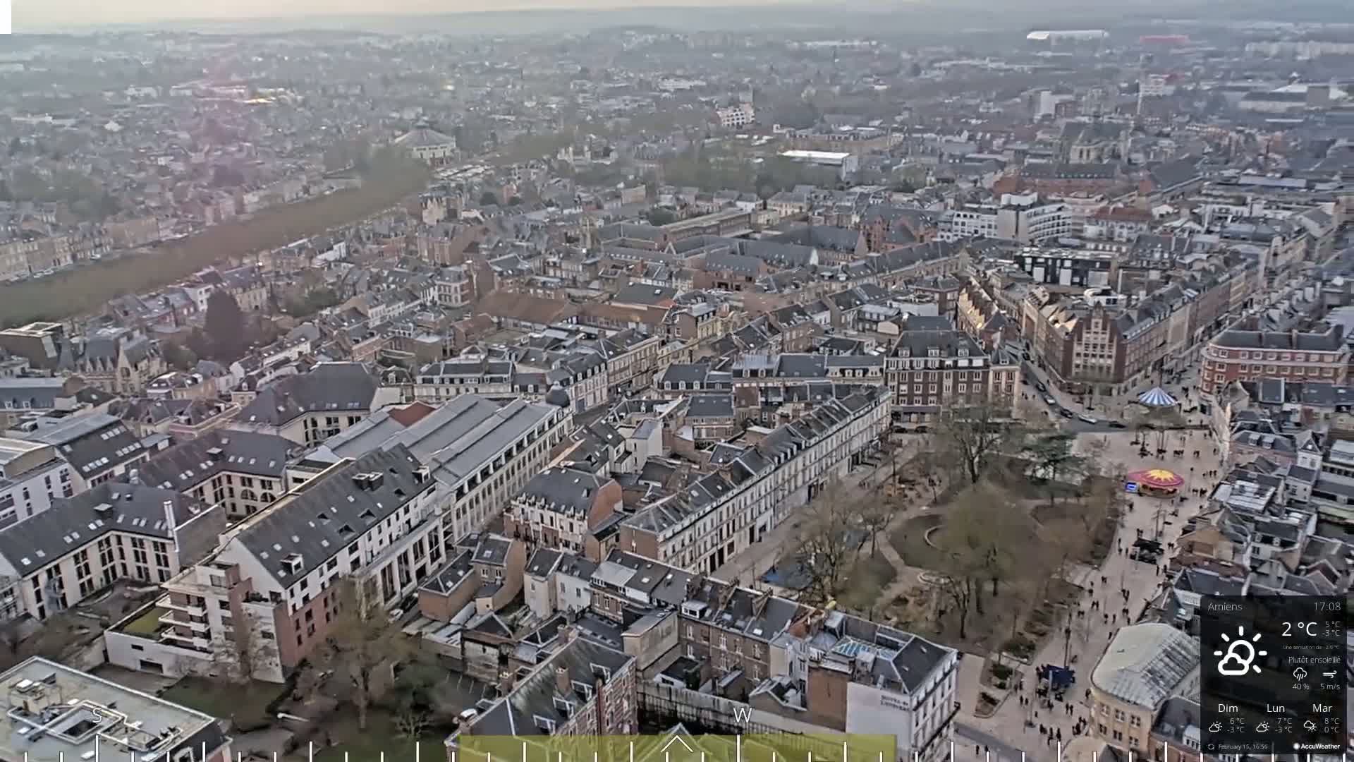 An aerial view of a city with many closely packed buildings under partly sunny skies.