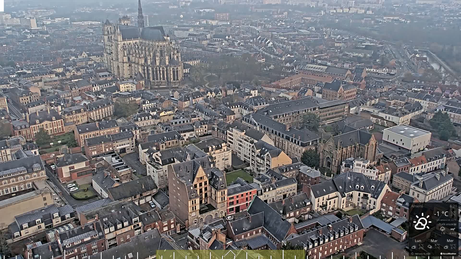 An aerial view of a European city on an overcast day shows a large cathedral and numerous closely packed buildings.