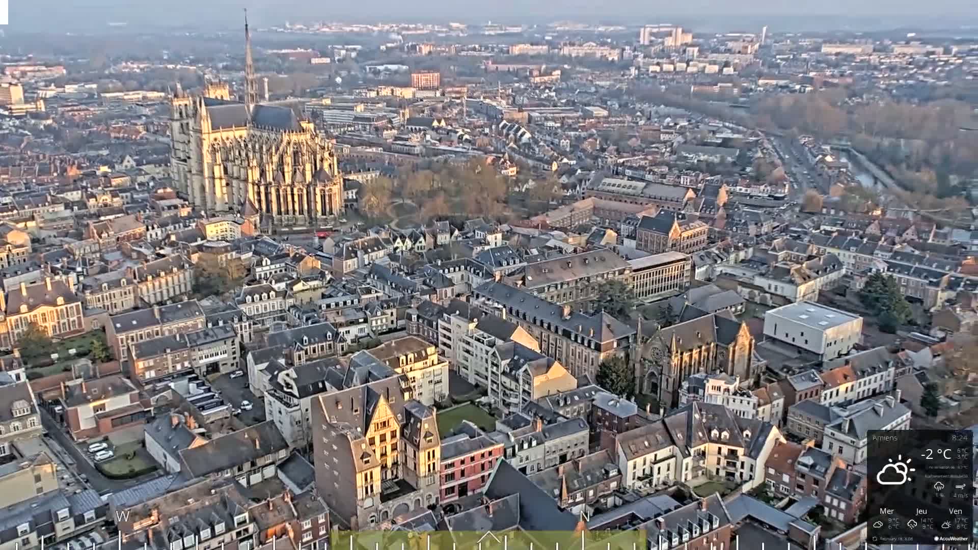 An aerial view of a European city on a partly sunny, cold day, showing a large cathedral and densely packed buildings.