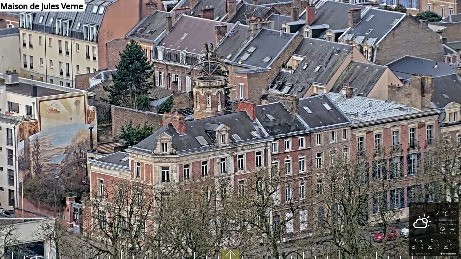 An aerial view of a city block featuring several multi-story brick buildings on a partly cloudy day.