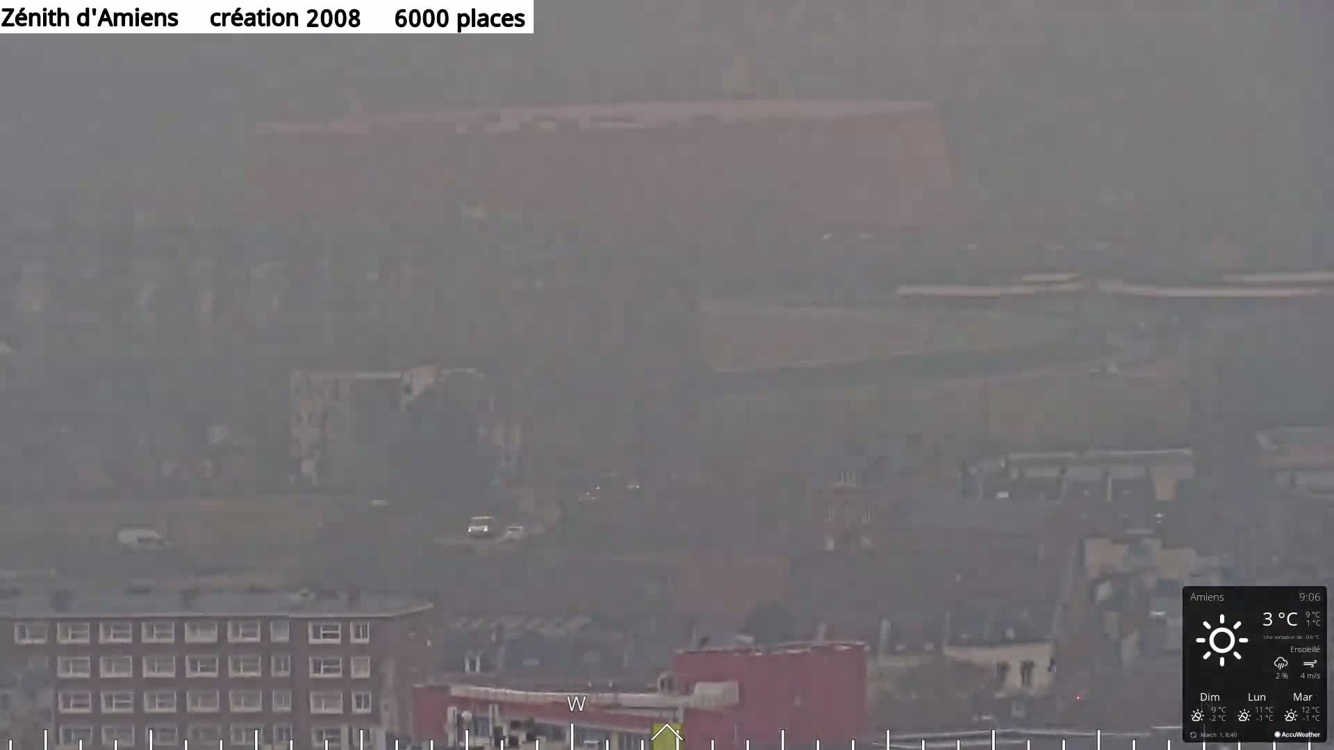 A hazy view of a city with buildings and roads partially obscured by atmospheric conditions, showing a large structure in the mid-ground.