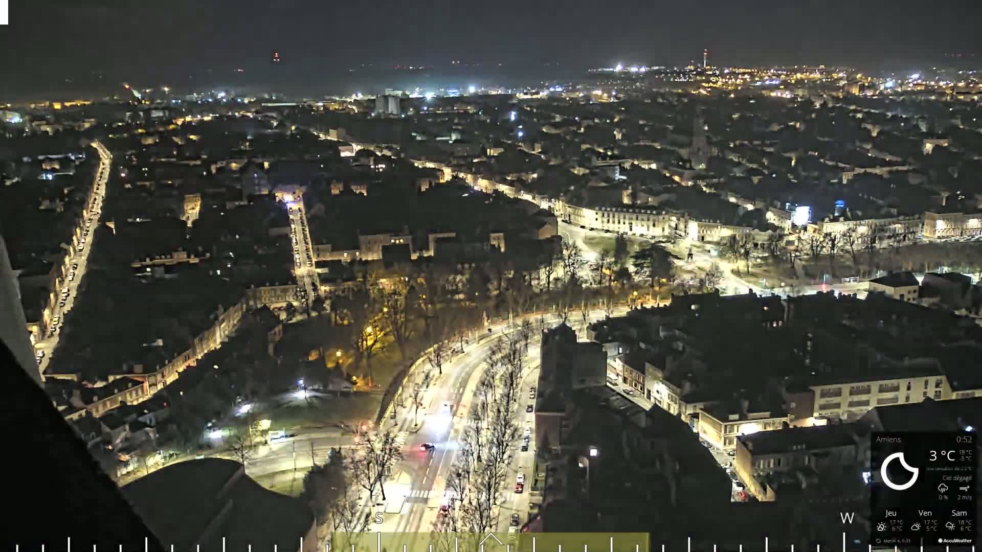 A nighttime aerial view of a city with brightly lit streets and buildings, under a clear sky.