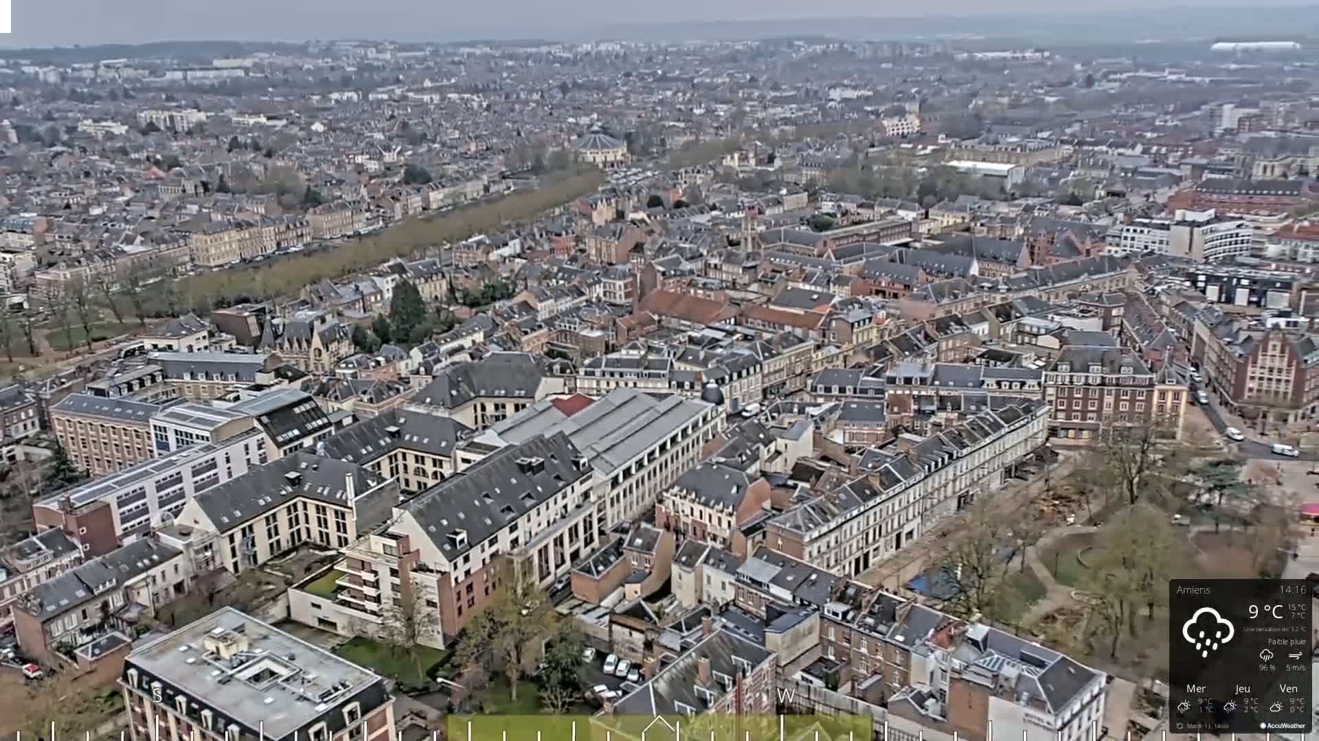 An aerial view of a densely populated city on an overcast day with light rain.