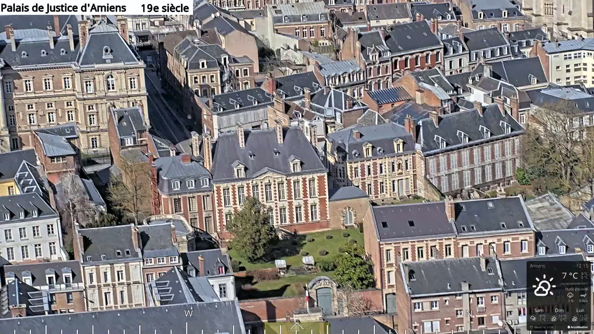 An aerial view of a city block of closely-packed, primarily brick buildings on a partly sunny day.