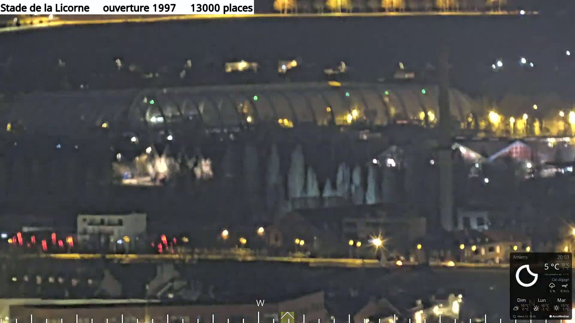 A nighttime view of a large stadium with lights illuminating the surrounding area under a clear sky.