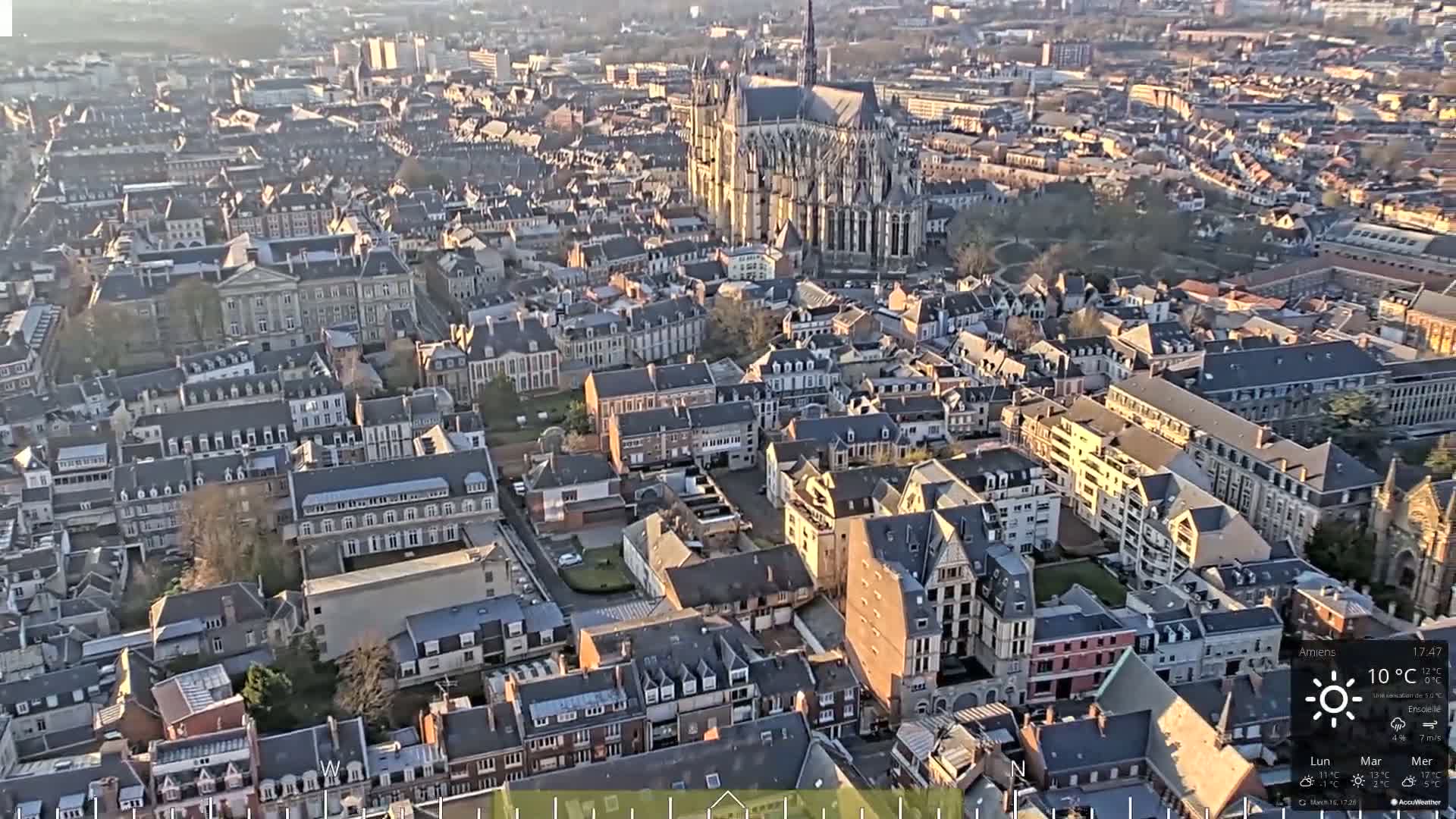 An aerial view of a European city on a sunny day, showing a large cathedral and many closely-packed buildings.
