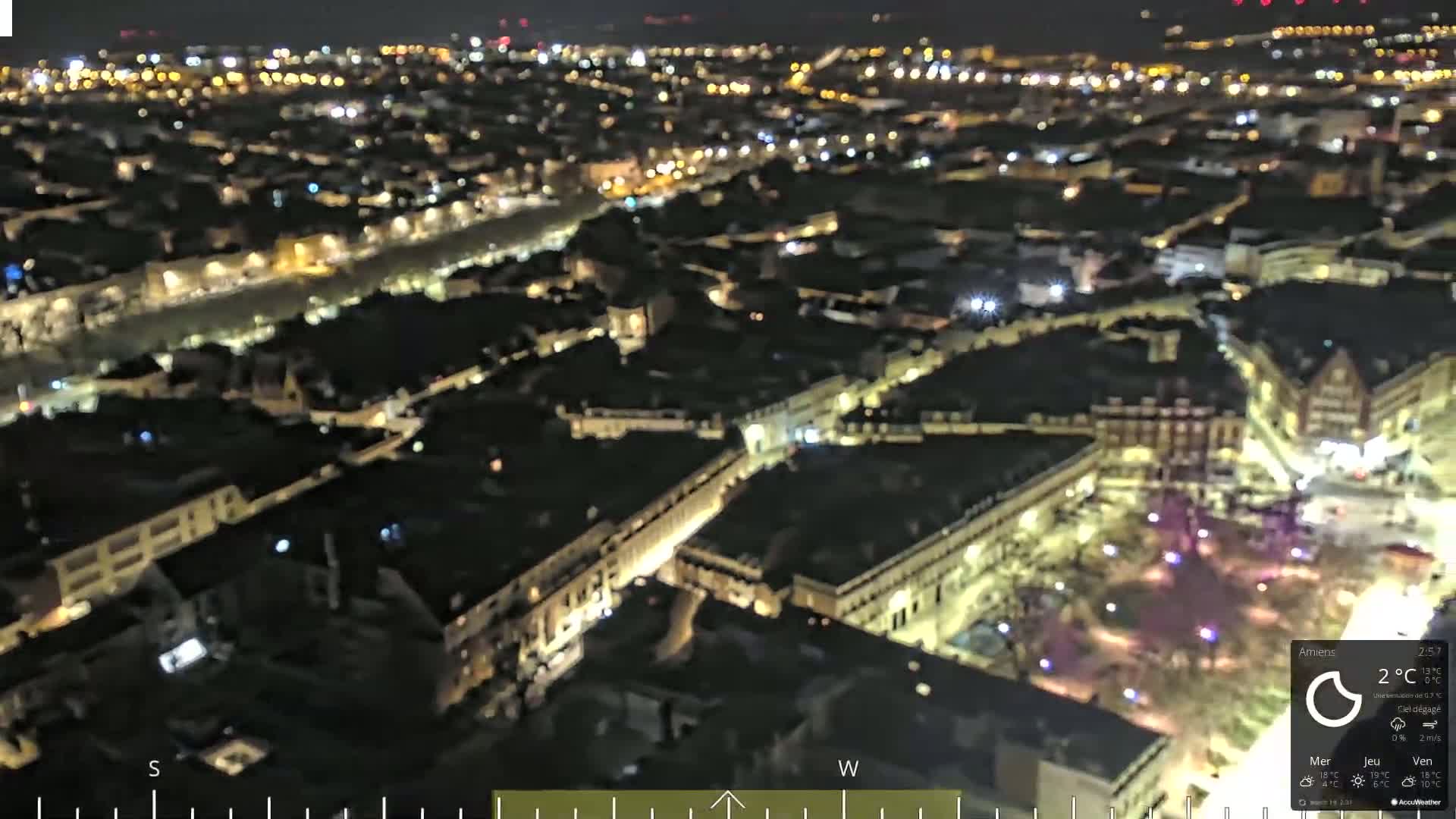 A nighttime aerial view of a city with many illuminated buildings and streets.