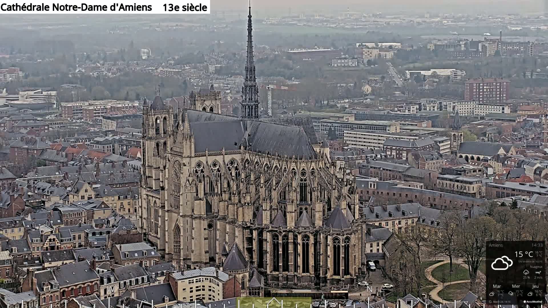 A large cathedral, surrounded by a city of closely packed buildings, is visible on an overcast day.