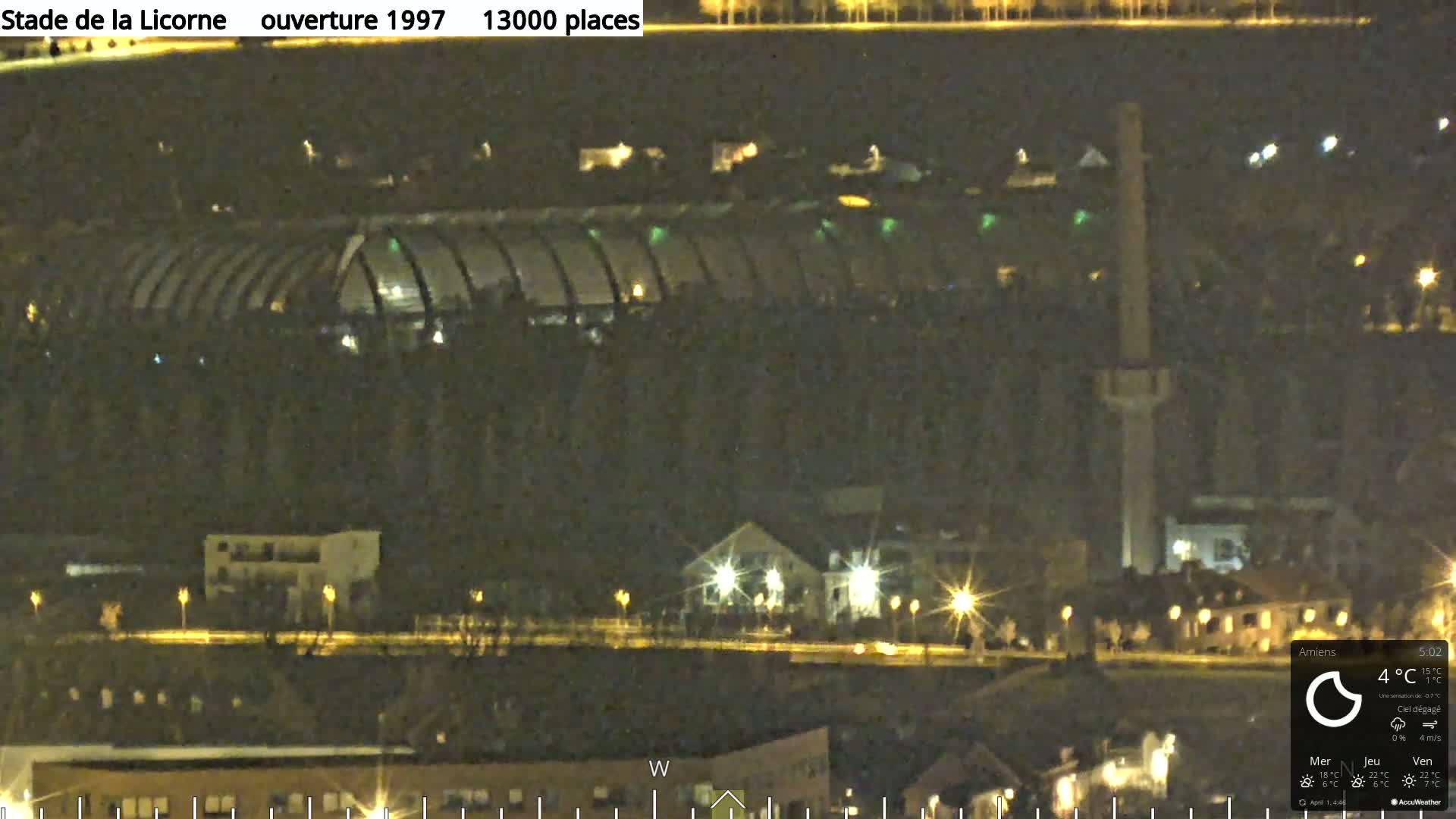 A nighttime long shot of a stadium and surrounding buildings, under a clear sky.