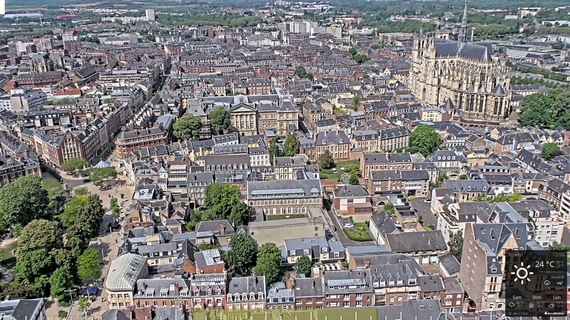A high-angle view of a European city on a sunny day, showing a dense collection of buildings and a large cathedral.