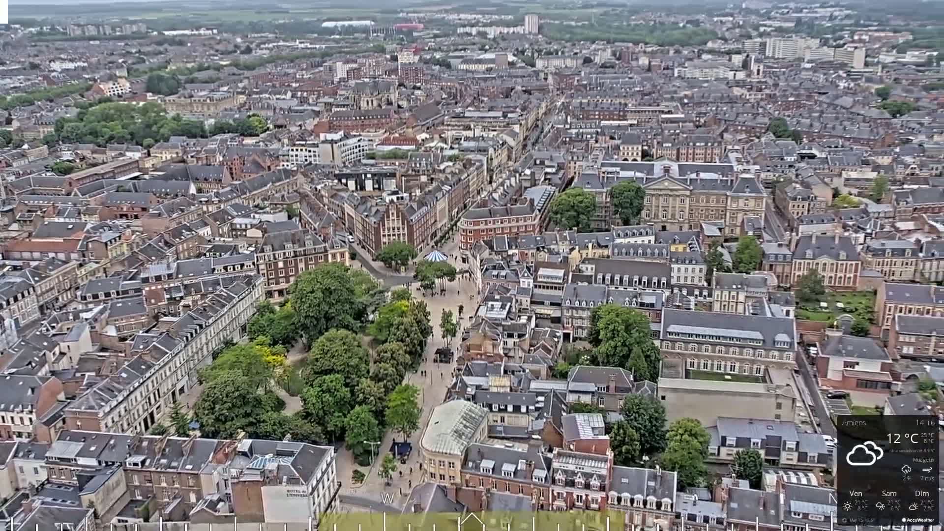 An aerial view shows a European city on a cloudy day, with a large park situated in the middle of densely packed buildings.