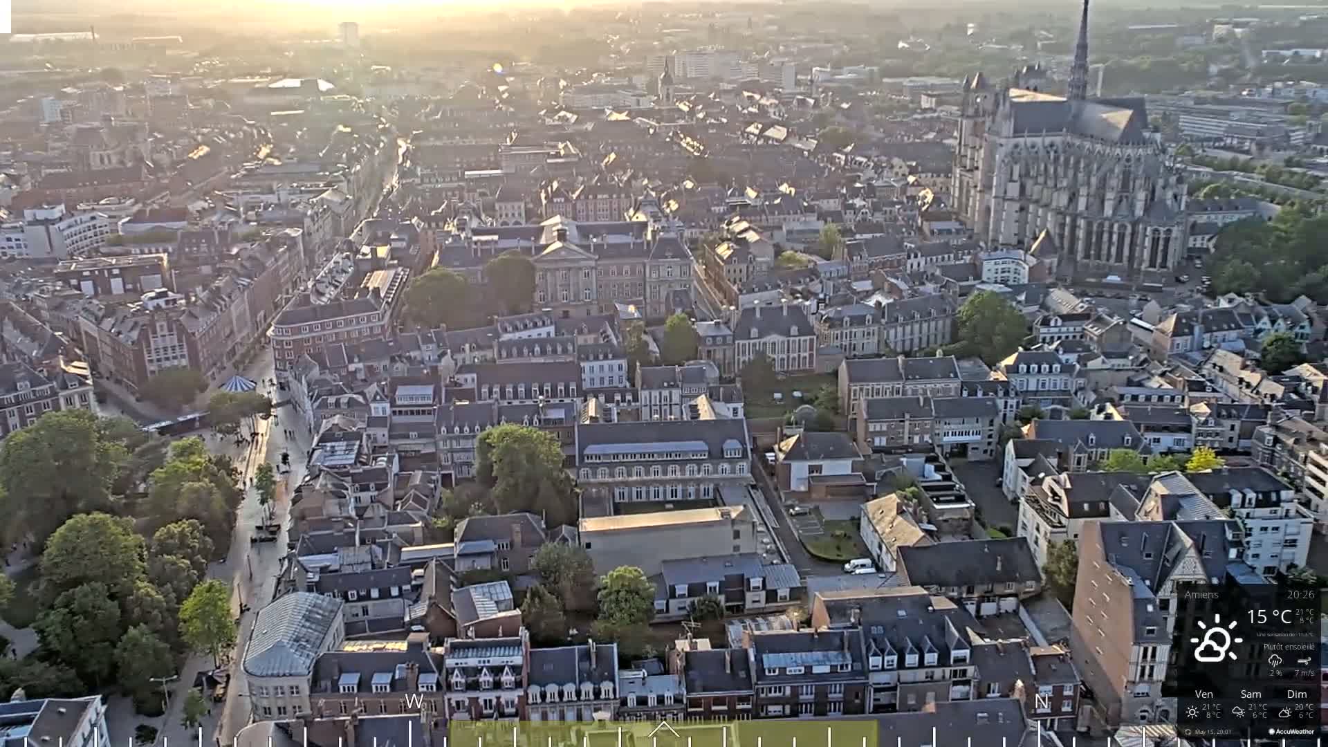A hazy sunset illuminates a dense cityscape with a large cathedral prominent in the background.
