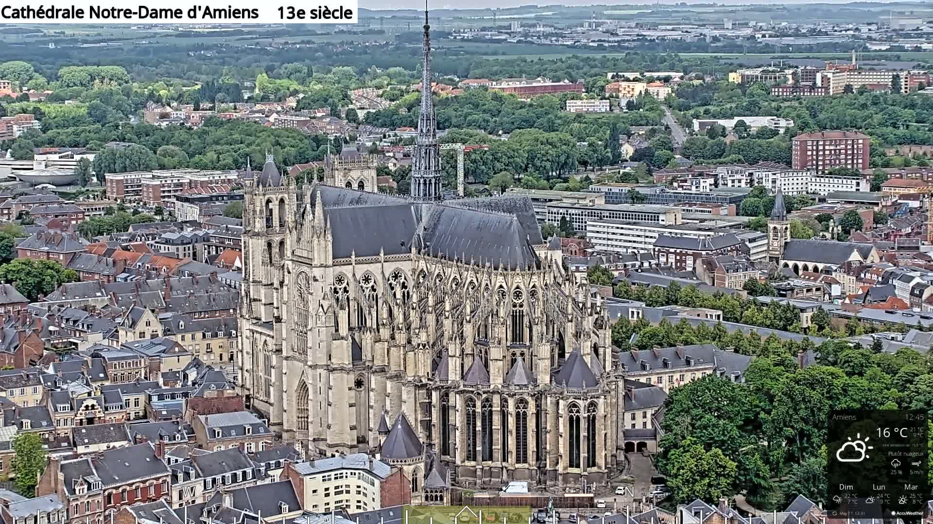 A large cathedral, situated among a densely packed city of low-rise buildings, under partly cloudy skies.