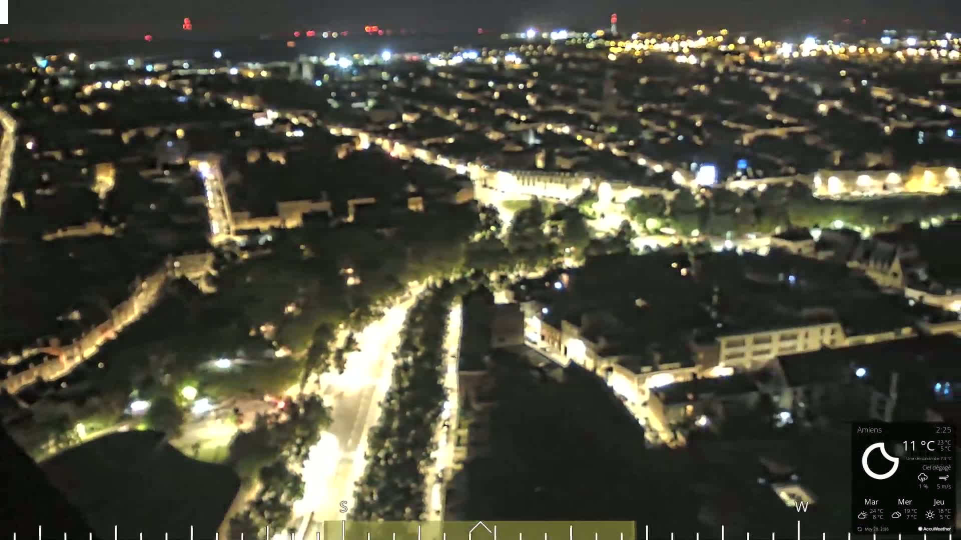 An aerial nighttime view of a city with illuminated streets and buildings under a clear sky.