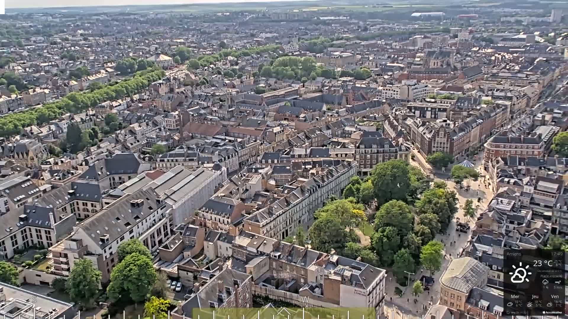 A high-angle, wide shot shows a densely populated city on a mostly sunny day.
