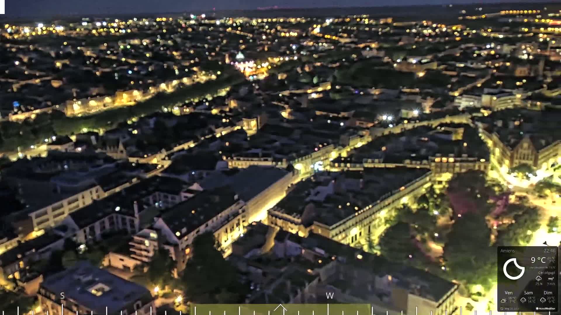 A nighttime aerial view of a city with illuminated buildings and streets under a clear sky.