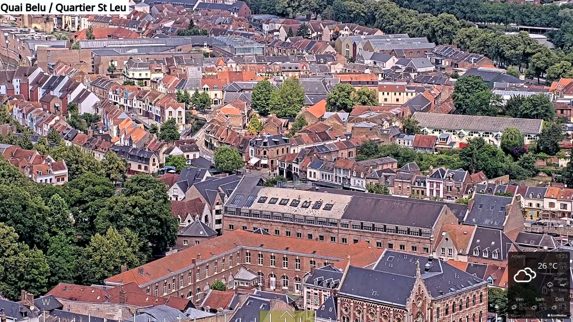 An aerial view of a densely packed European city on a partly cloudy day.