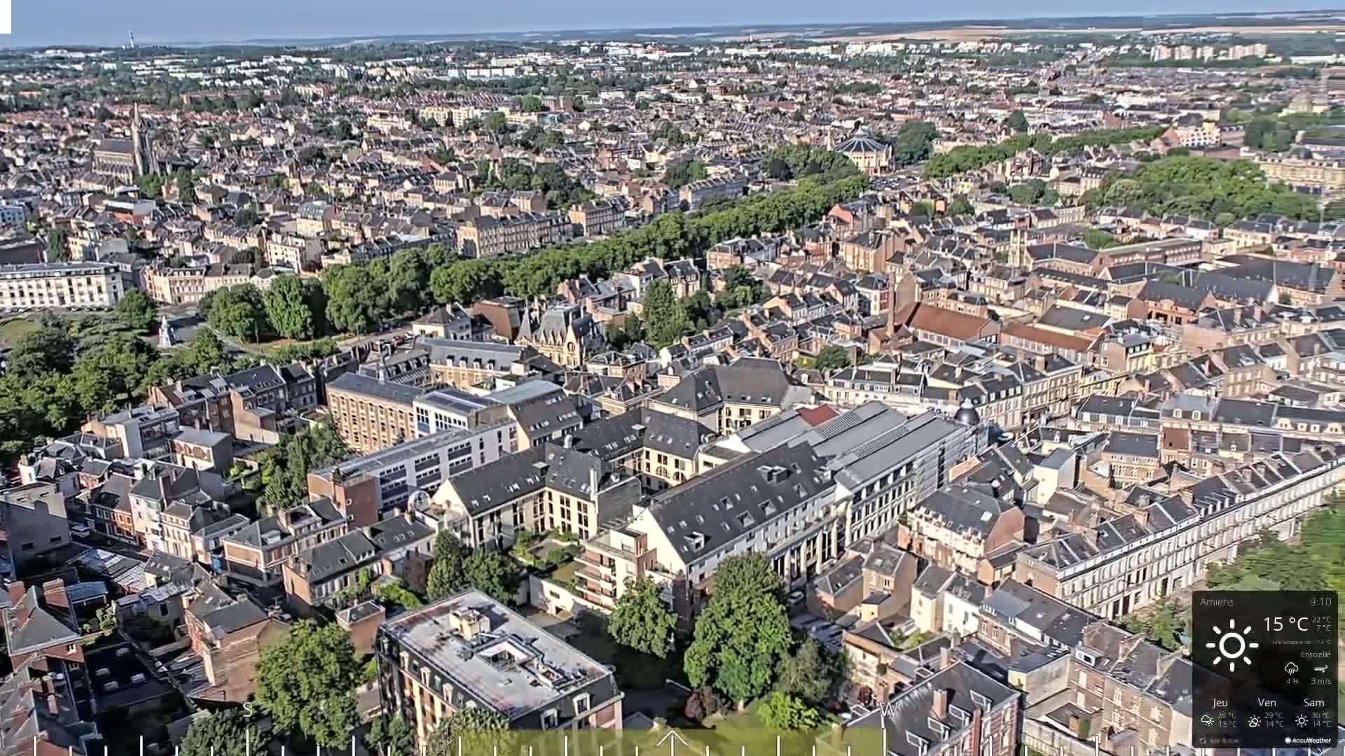 An aerial view of a densely populated city with predominantly brown-roofed buildings on a sunny day.