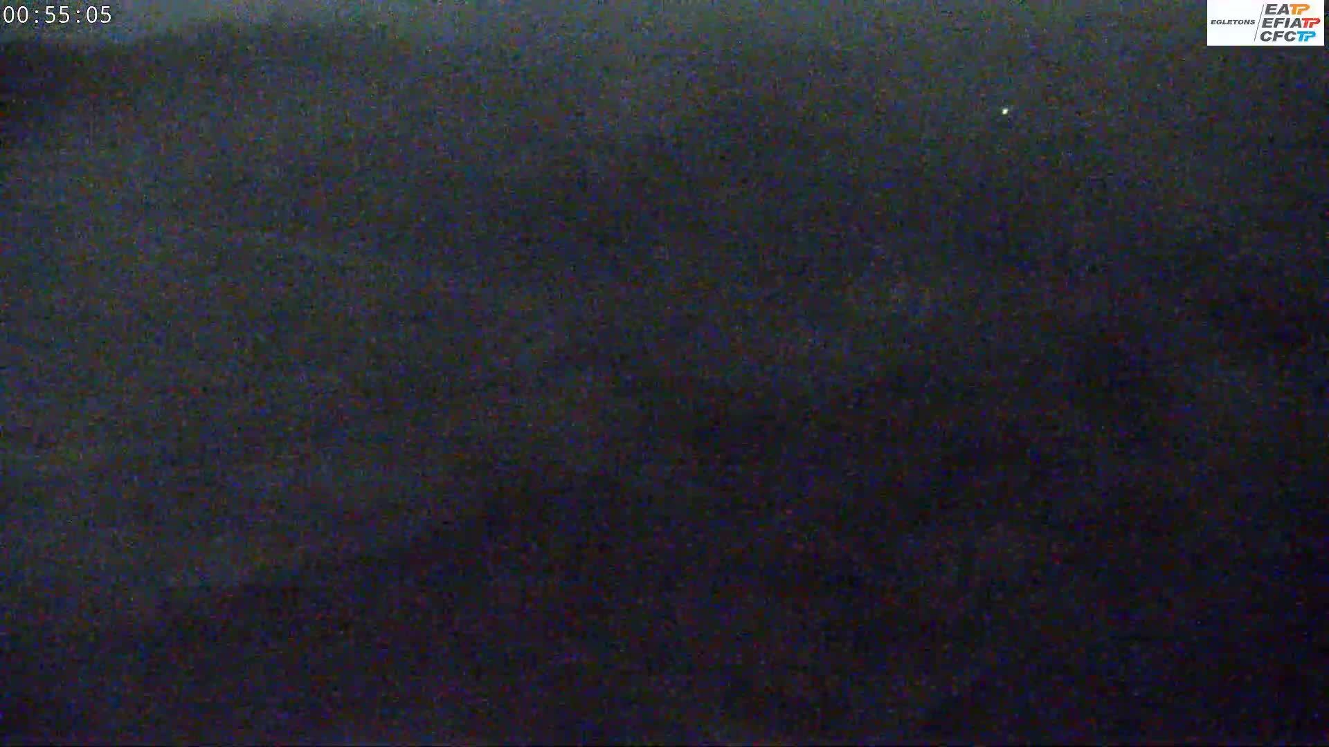 A dark, grainy image shows a mostly black night sky with a single, faint light visible.