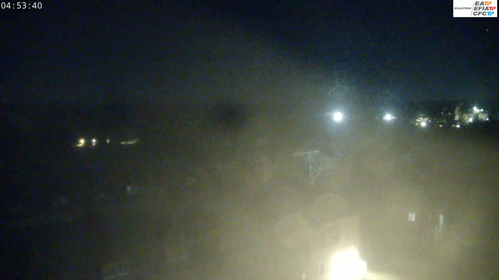 A hazy, dark night scene shows distant lights and a dimly lit foreground.