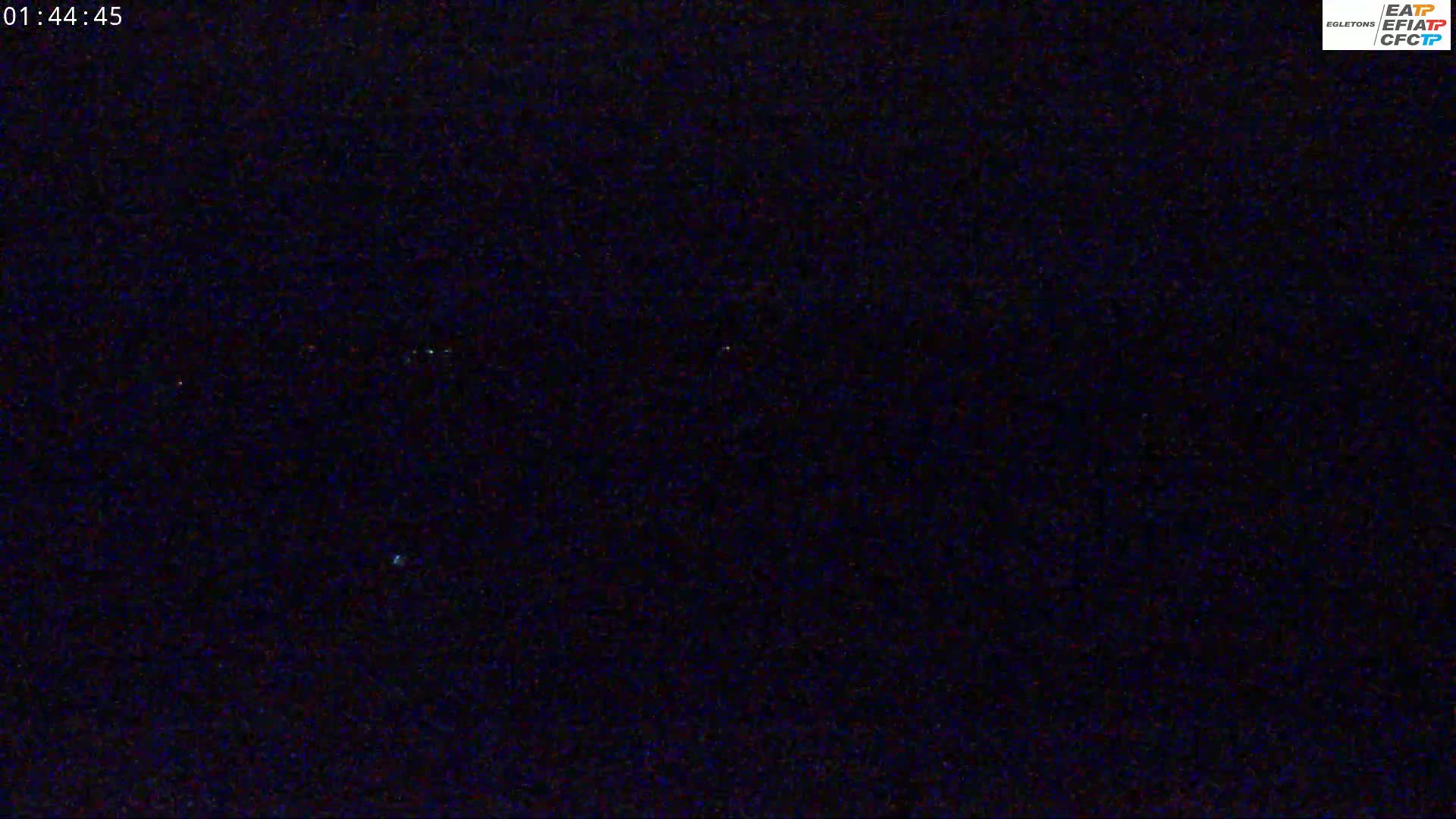 A dark nighttime scene shows a few faint lights in the distance.