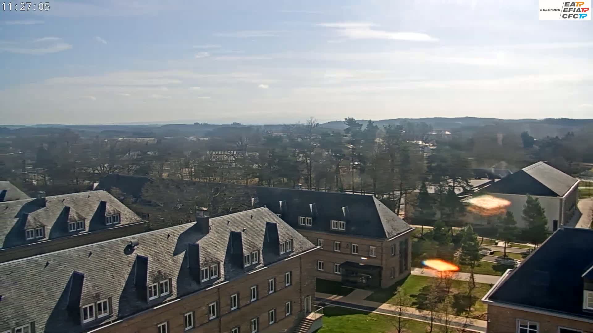 A high-angle, long shot of a campus with several brick buildings under a mostly sunny sky.