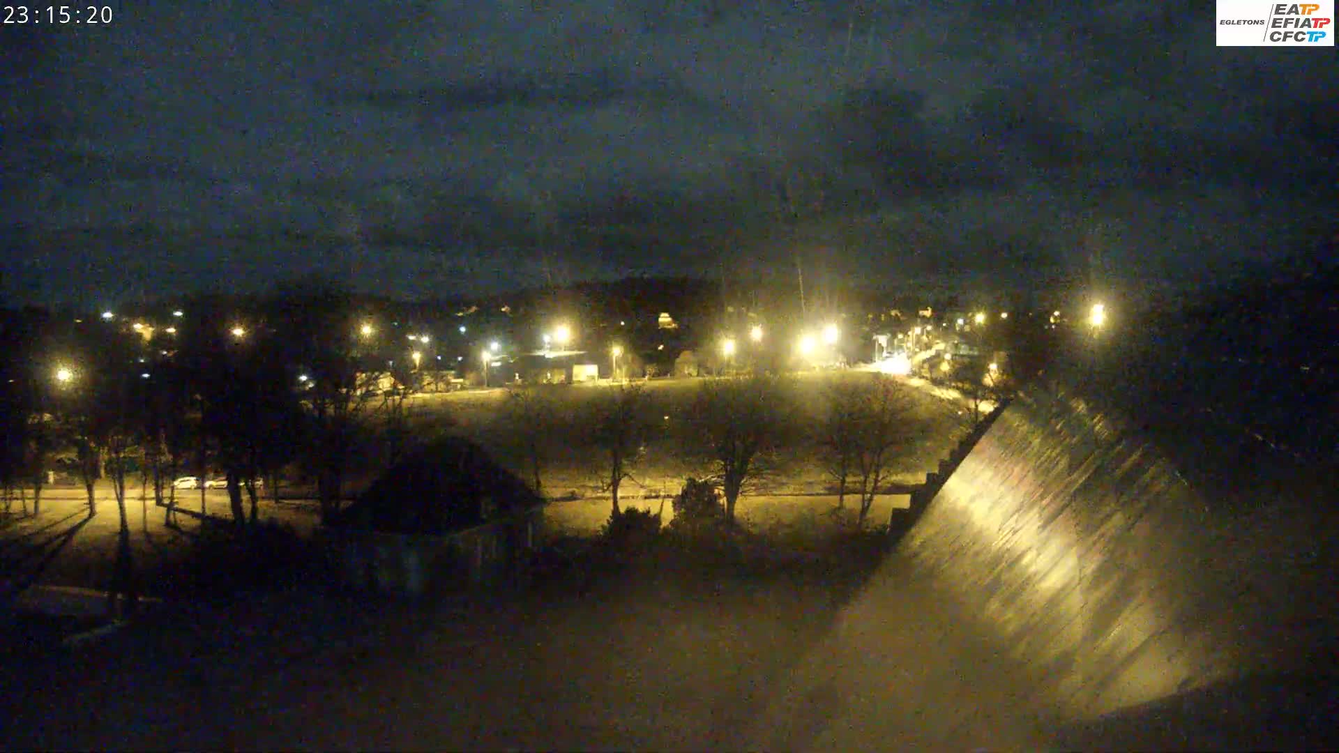 A nighttime view of a park and dam under a partly cloudy sky.