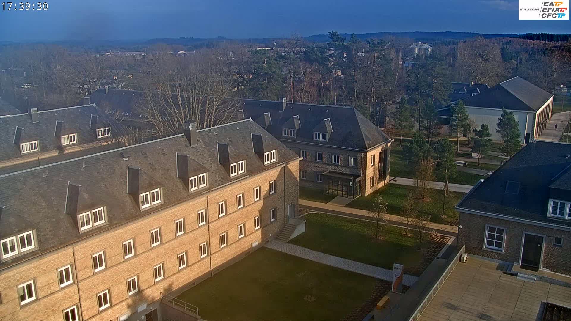 An aerial view of several low-rise buildings on a campus-like setting under a clear, sunny sky.