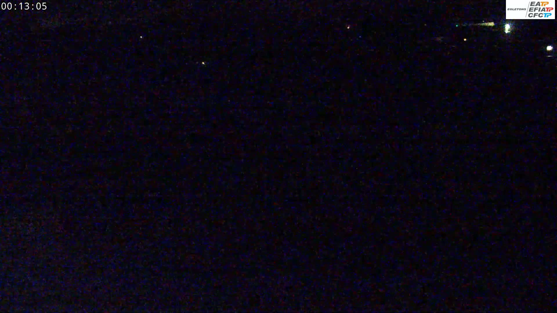 A nighttime view shows a dark, mostly featureless landscape under a clear sky.