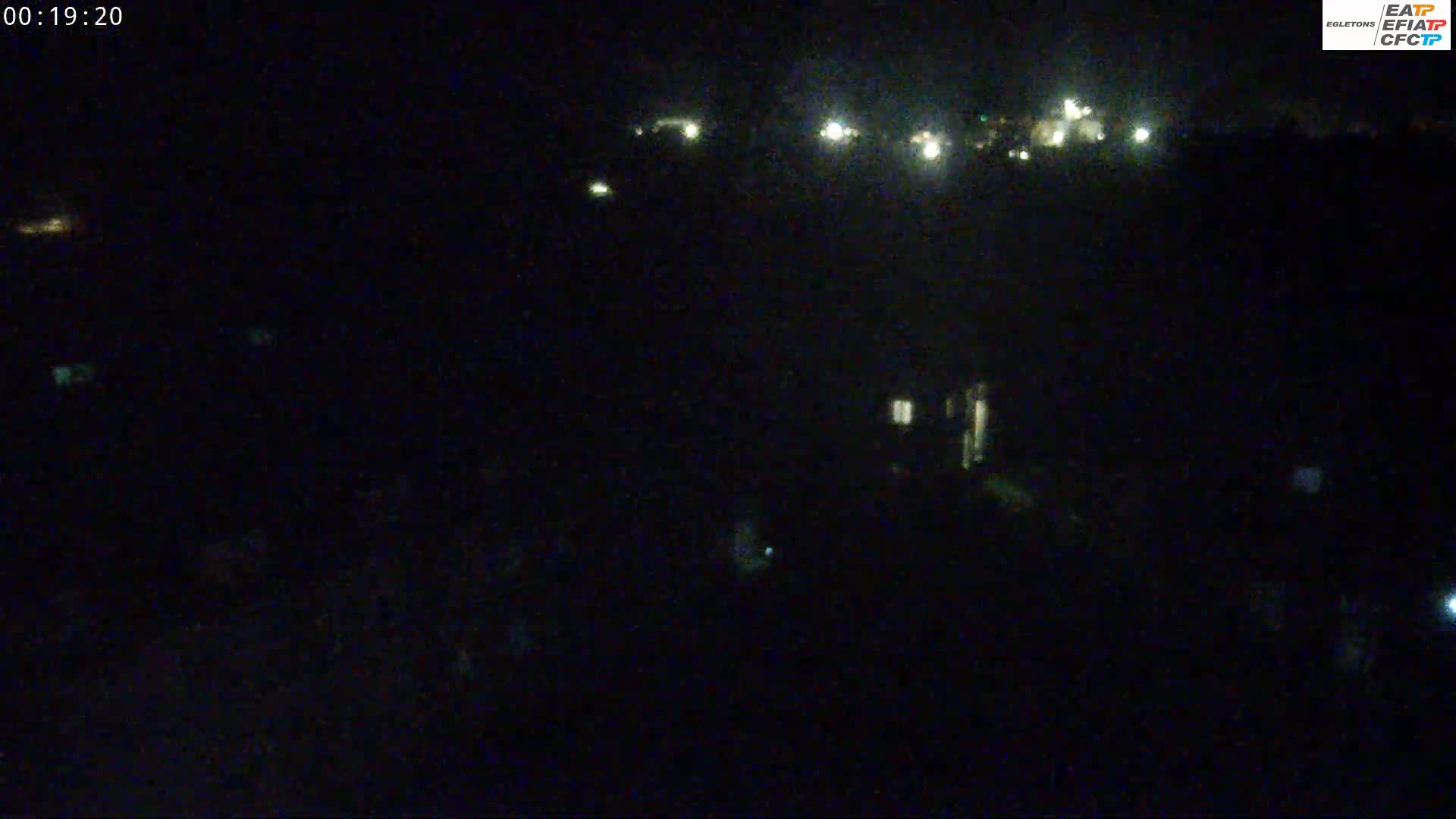 A nighttime, long-range view shows dimly lit buildings and sparse lights in the distance.