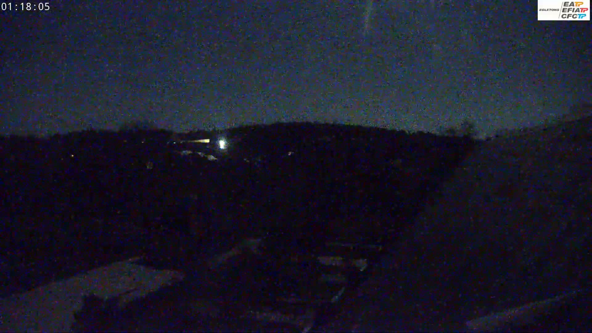 A dark, nighttime scene shows a mostly obscured landscape under a clear, dark sky.