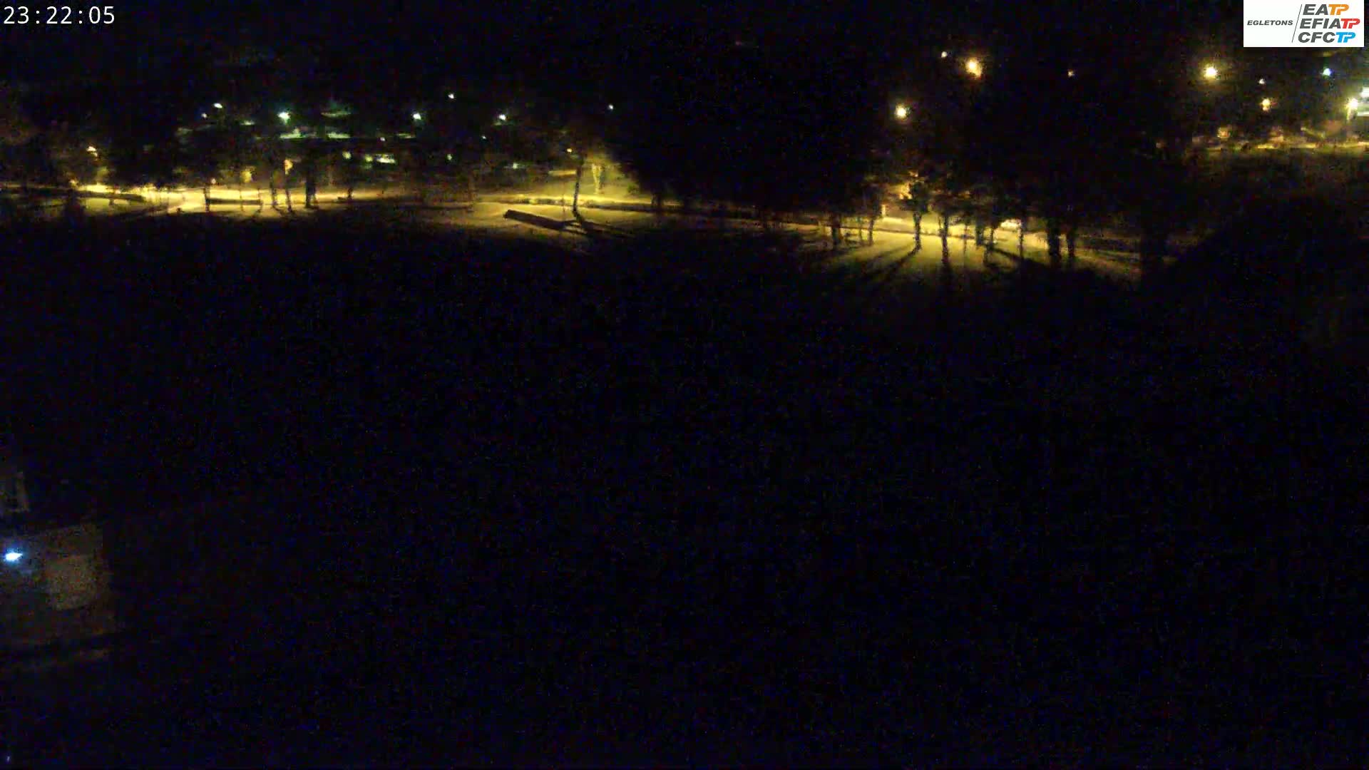 A nighttime view of a park with illuminated trees and paths, under clear skies.