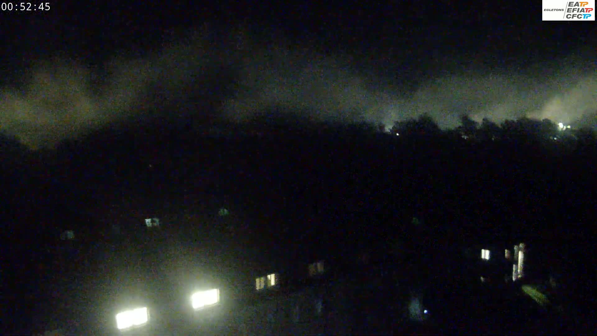 A nighttime view of dimly lit buildings under a cloudy sky.