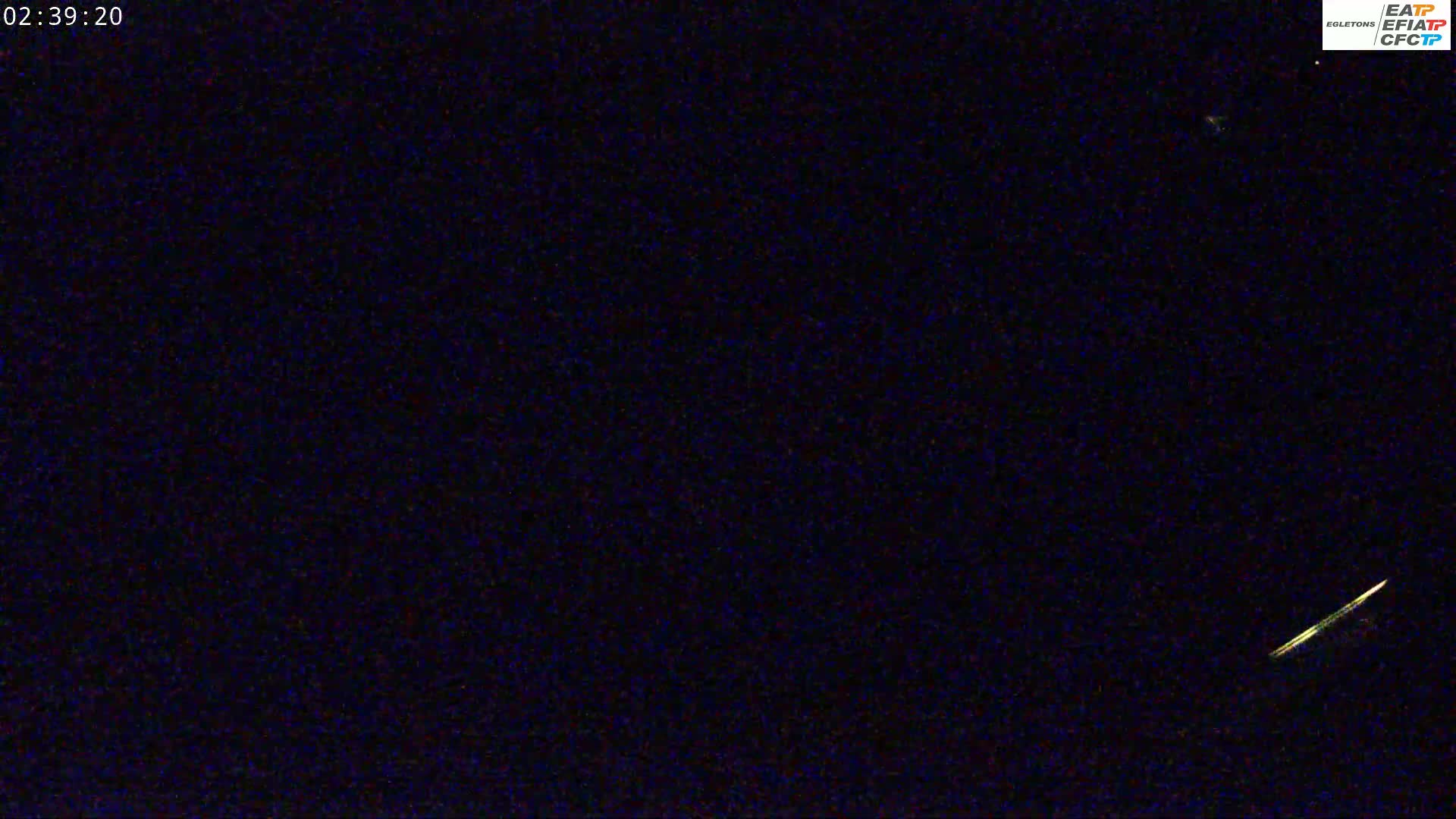 A bright streak of light, possibly a meteor, is visible against a dark night sky.