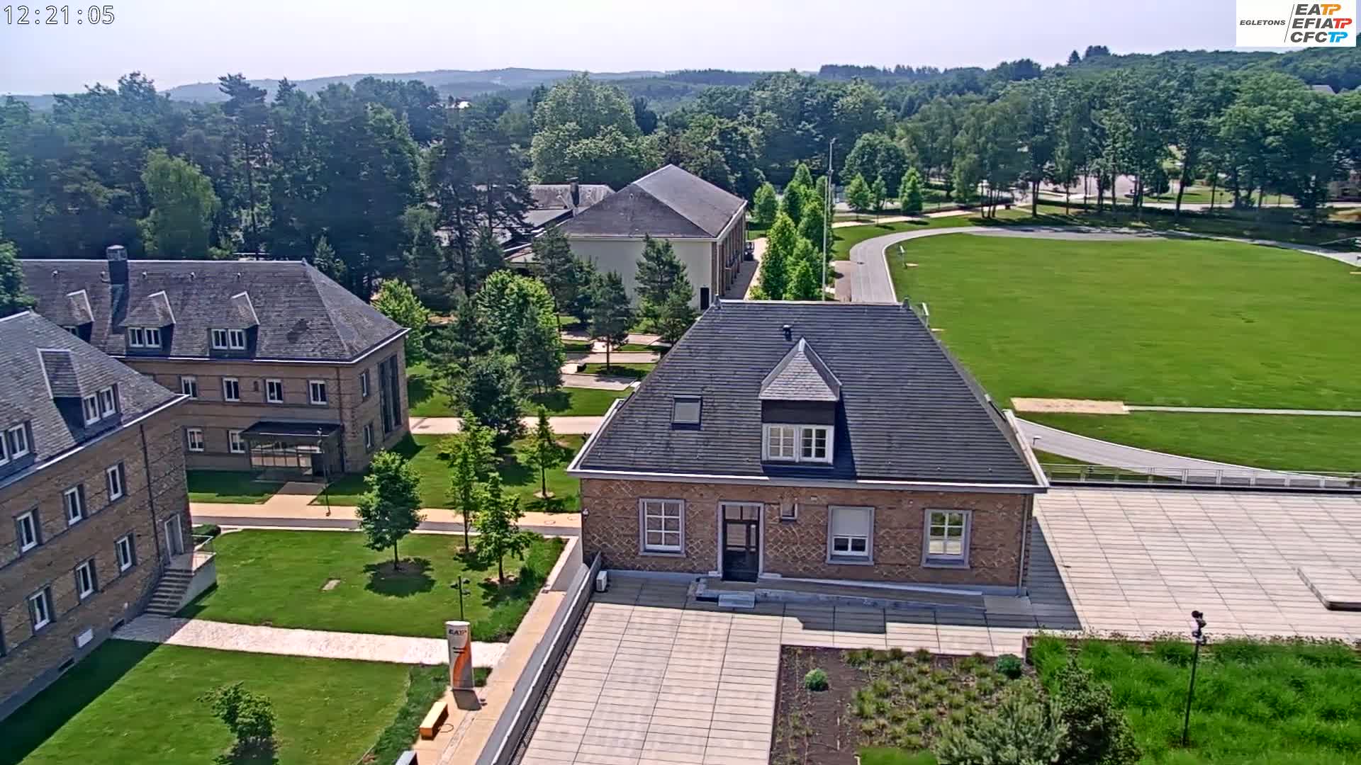 An aerial view of a campus on a sunny day shows several brick buildings surrounded by green lawns and trees.