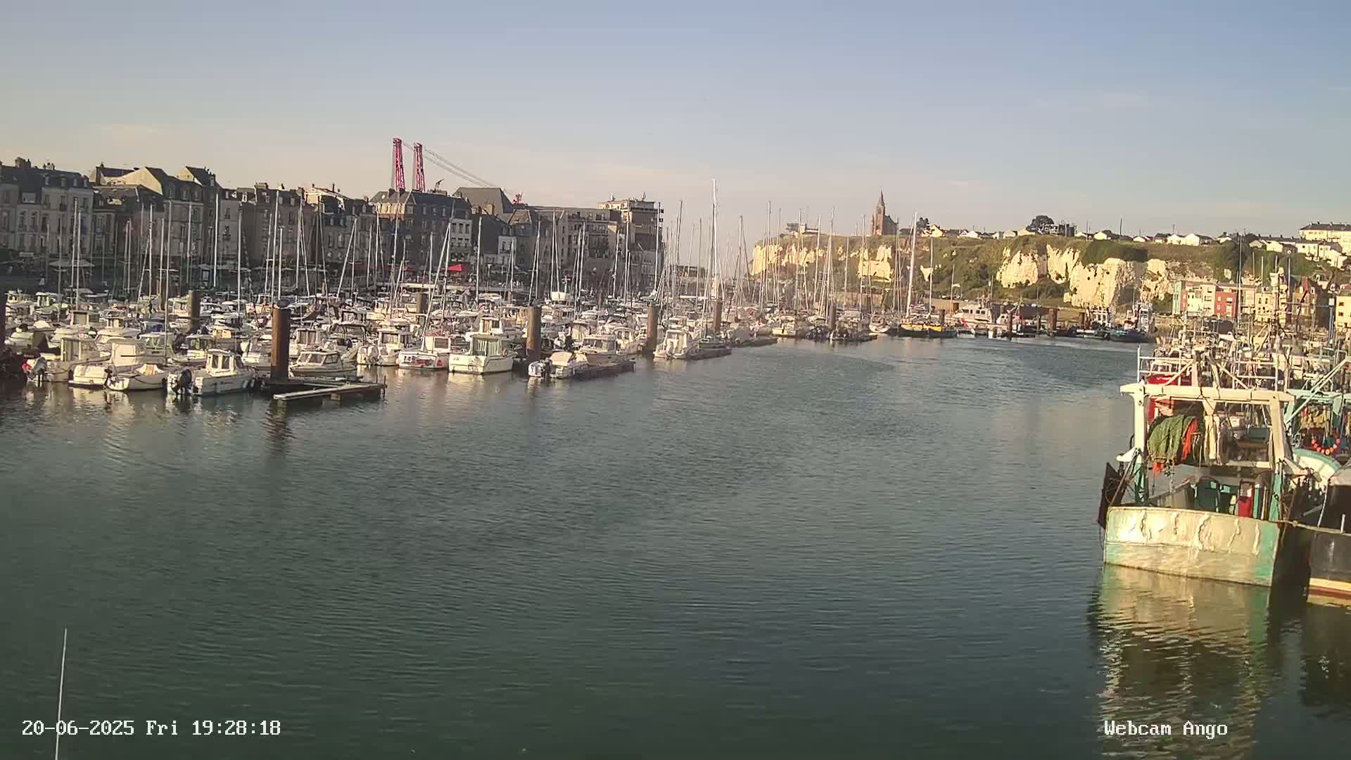 A harbor filled with many sailboats and fishing boats under a clear sky.
