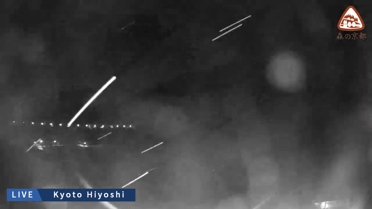 A blurry night scene reveals numerous bright, streaking lights, likely from vehicles and distant streetlights, obscured by what appears to be heavy rain or snow.