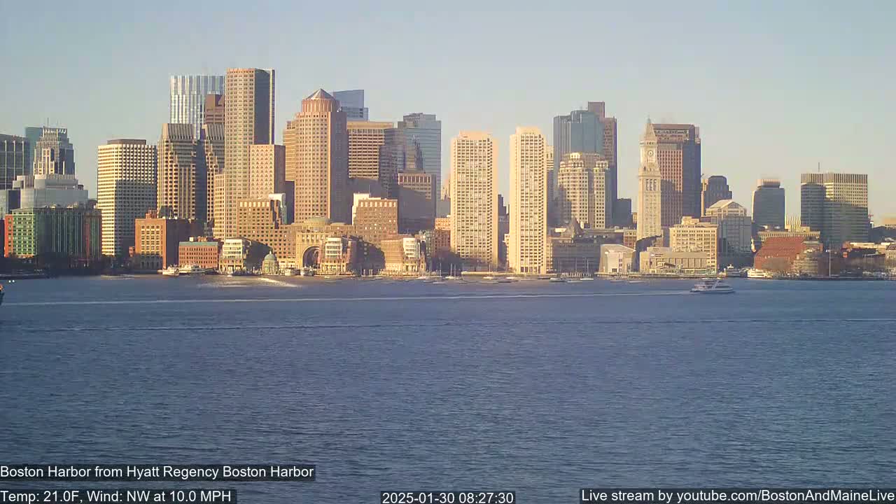 A city skyline with numerous skyscrapers is visible across a body of water under a clear, bright sky with a northwest wind of 10 mph and a temperature of 21°F.