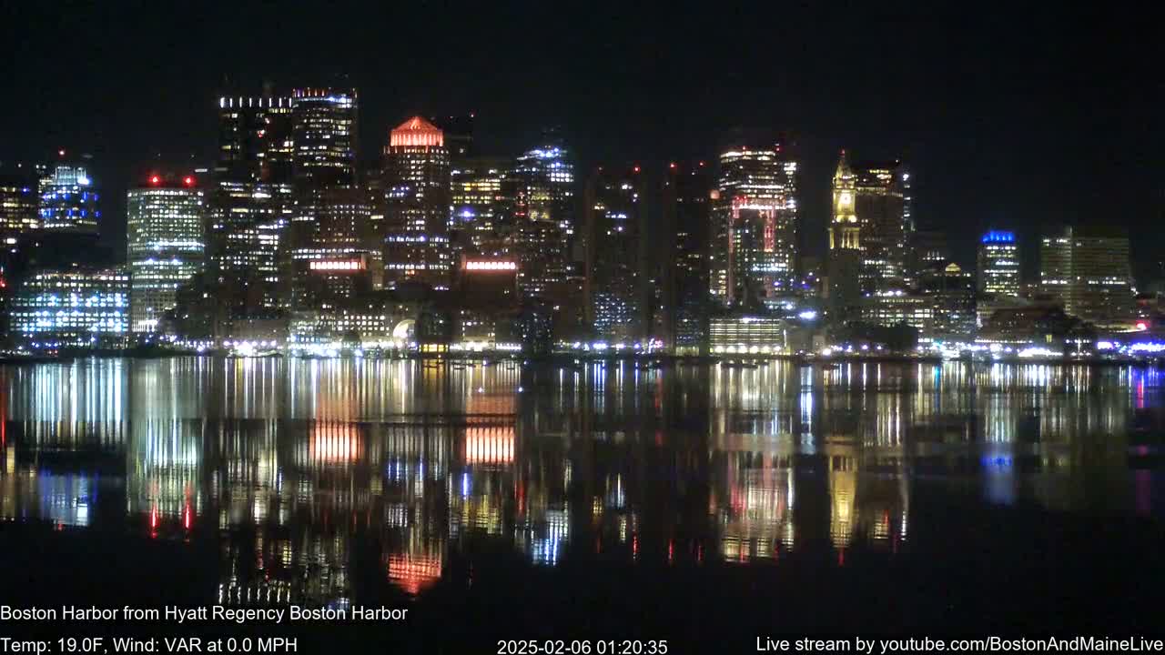 A nighttime view of a brightly lit city skyline reflected in calm water.